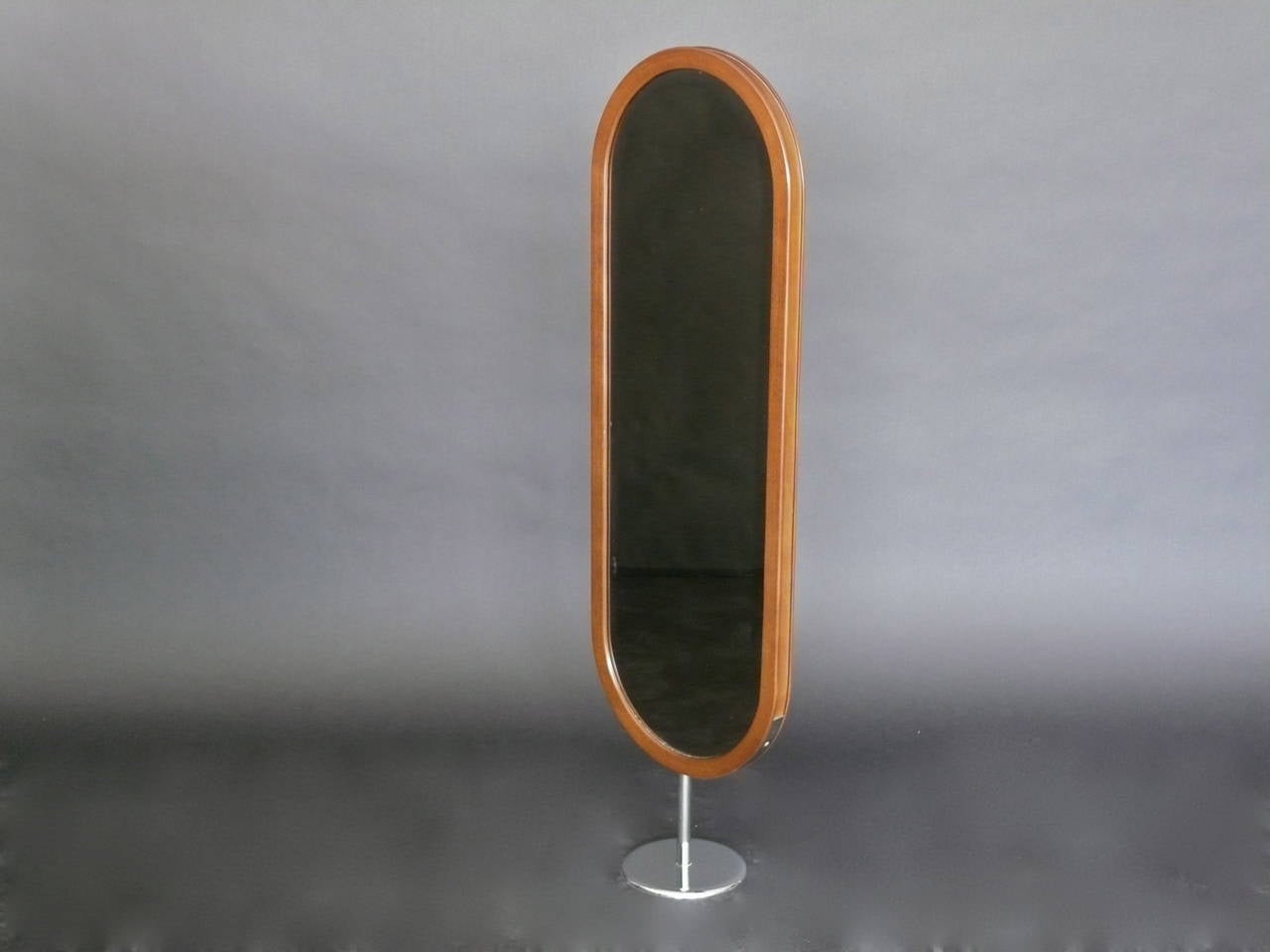 Slender German floor mirror made of teak and resting on a circular chrome base. Wood and glass in excellent vintage condition. Small scale. Perfect for a child's room.