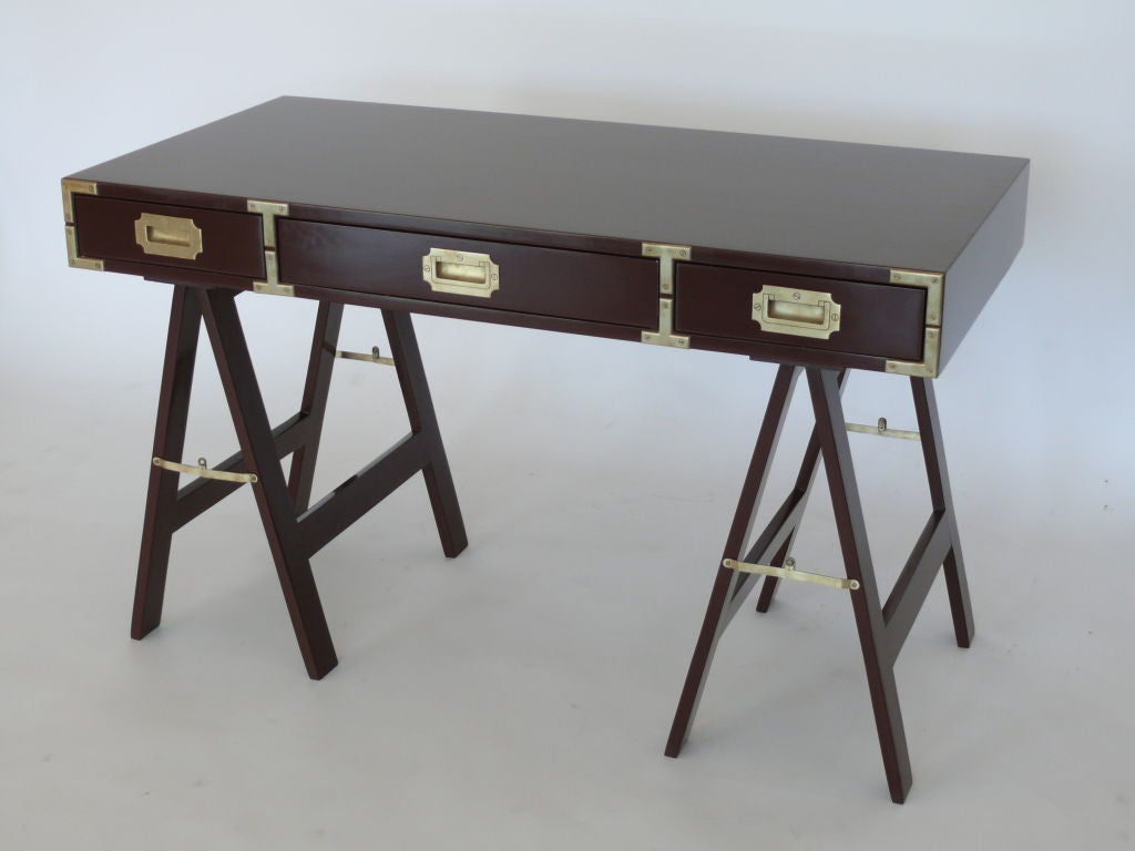 Deep maroon lacquered campaign desk with brushed brass hardware and sawhorse legs. Perfect for a writing desk!
