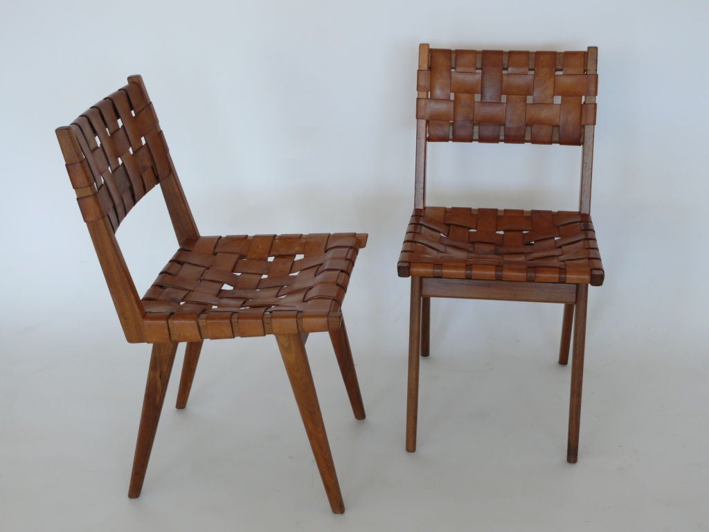 Stunning set of 4 leather and wood chairs including two armchairs. Rich oiled brown leather straps woven on seat and back with beautiful tapered walnut wood legs. A unique find!