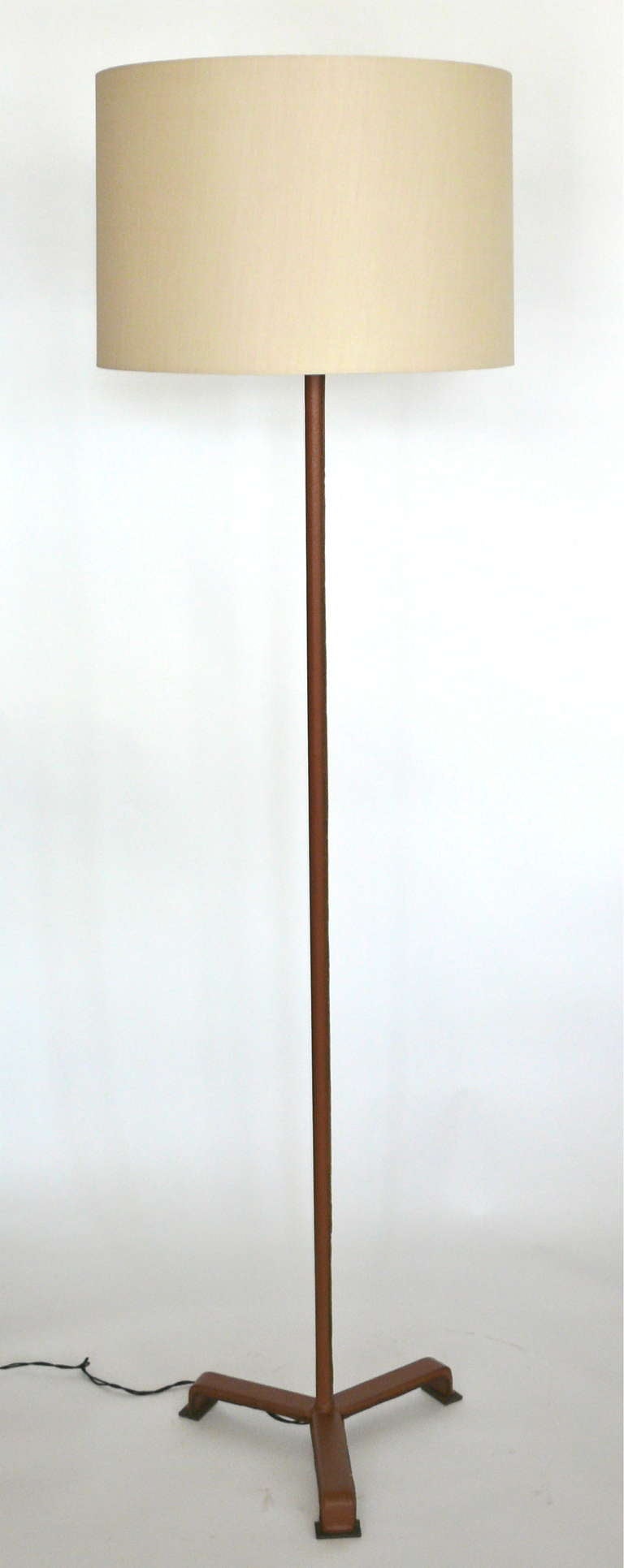 Handsome Jacques Adnet floor lamp, fully covered in a rich light brown leather with stitching. Leather has been newly dyed. Newly re-wired and new silk shade.