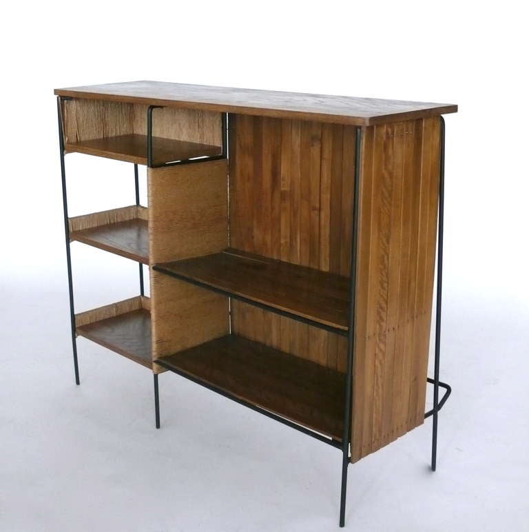 Unique free standing bar by Arthur Umanoff. Black iron frame with newly added solid white oak top and shelves. Front of bar has original oak slatted panels and iron foot rest. Open shelving with woven accents allows for nice display barware. Also