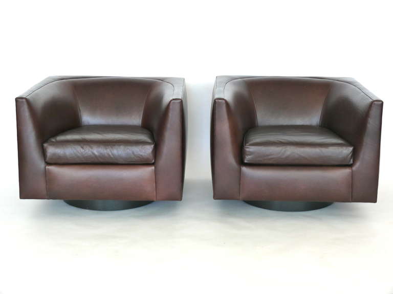 Stunning pair of leather swivel chairs. Newly upholstered in a deep chocolate brown leather. Chair rests on a walnut wood swivel base that has been newly refinished in a ebony black stain. Extremely comfortable and sleek modern design.