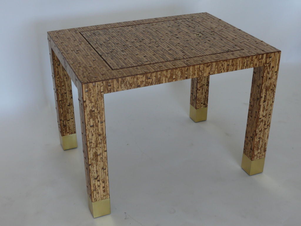 Unique bamboo game table in the style of Karl Springer. Fully covered bamboo table with large brass capped legs. Top of table has solid brass loop to lift off top. Stunning leather backgammon board with brown and yellow game pieces.