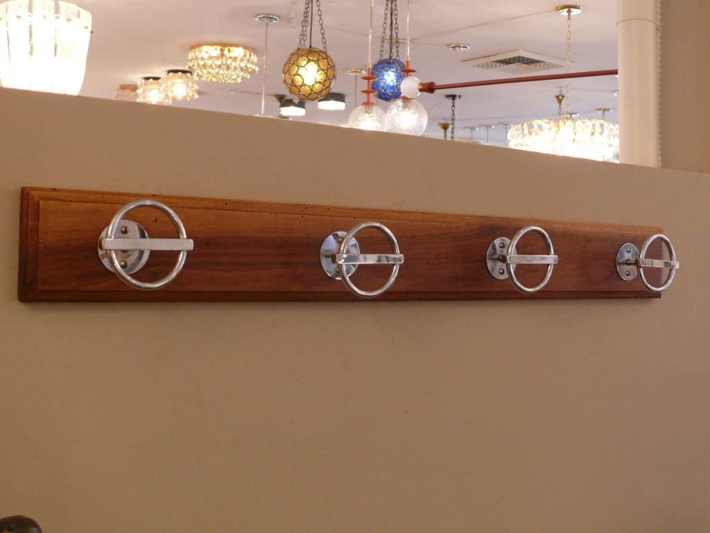 Stunning and classic Jean Royere coat rack with 4 individual aluminum circular hooks on walnut wood plank. Signed with impressed markings to reverse on each hook.