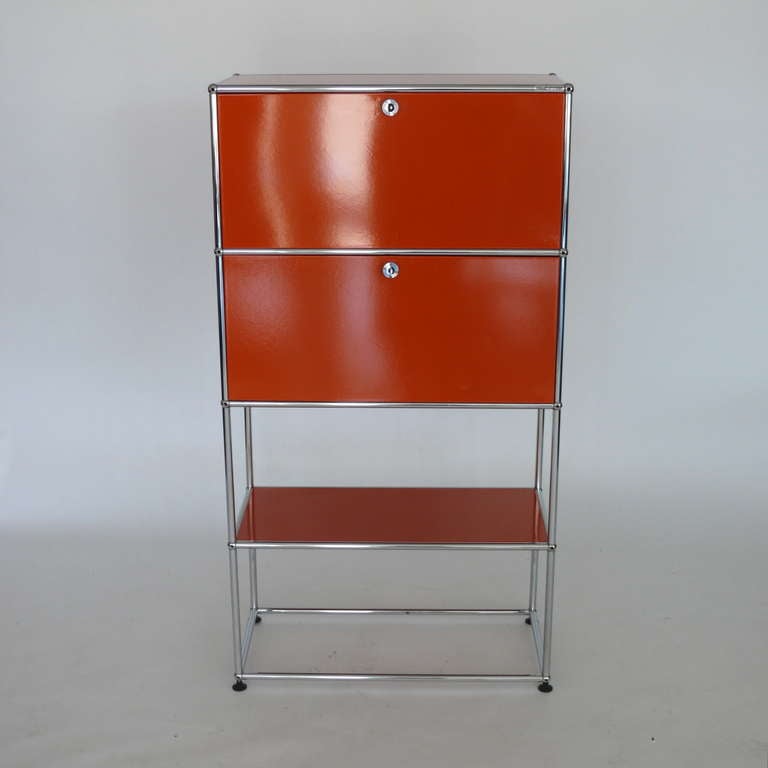 Fantastic bright red lacquered cabinet by Fritz Haller for Herman Miller. Newly lacquered metal panels connected by chromed steel fittings, one drop-front over one sliding drawer and open shelf. Open floating base makes for nice design. Fun and