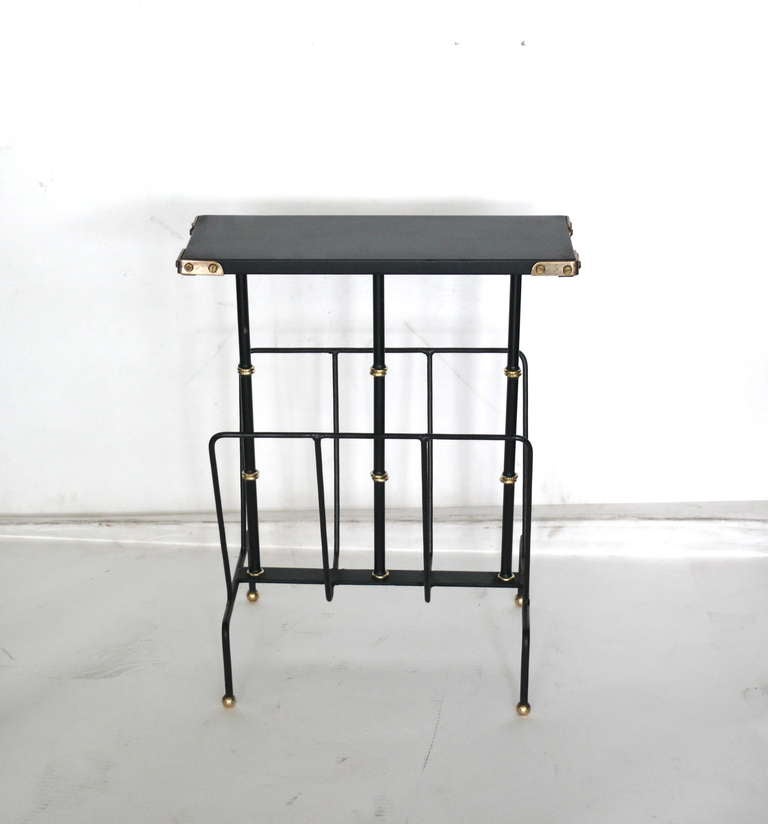 Handsome Jacques Adnet side table and magazine rack. Original skai top with brass corners rests on three iron and brass bamboo supports. Lower iron magazine rack on four leg iron base with brass ball feet. Stunning accent piece.