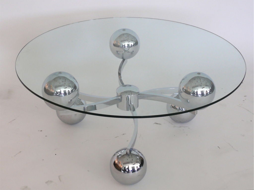 French chrome coffee table with floating glass top, the body made of six chrome globes orbiting in two tiers from a cylindrical center piece. A beautiful statement table.
