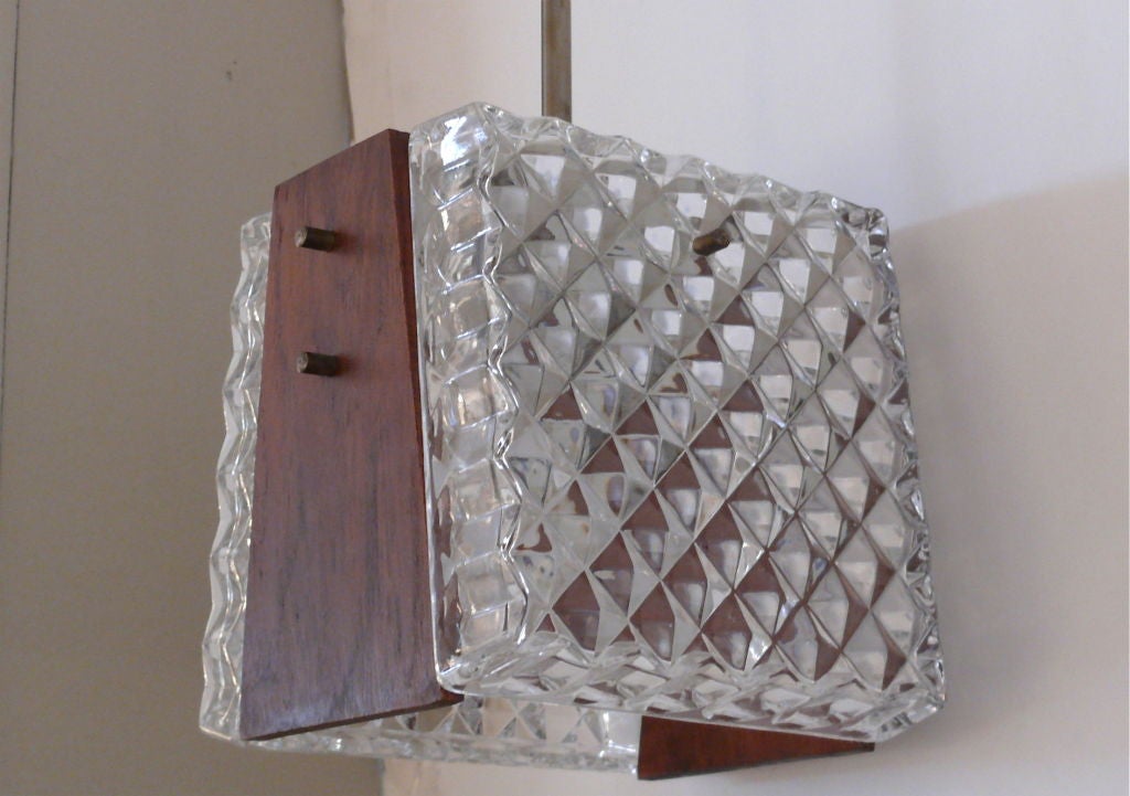 Fascinating crystal and wood pendant, the crystal body covered in a geometric diamond pattern and holding two tapering wood side panels. Extremely stylized.