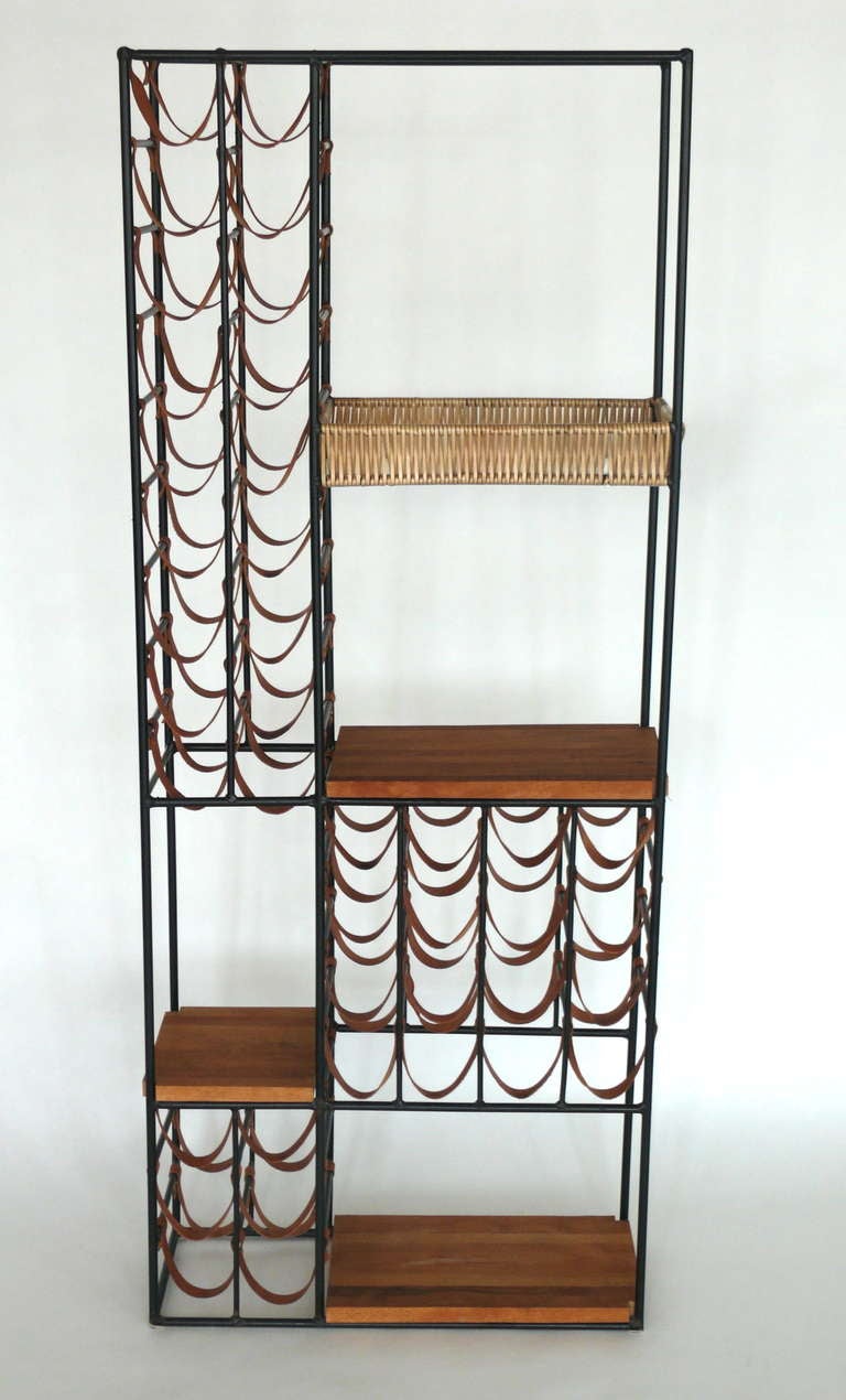 Large Arthur Umanoff wine rack wall unit constructed of original saddle brown leather straps, black iron, butcher block wood, and wicker. Four separate surface spaces and holds 38 bottles of wine. Great function and craftsmanship. Two available.