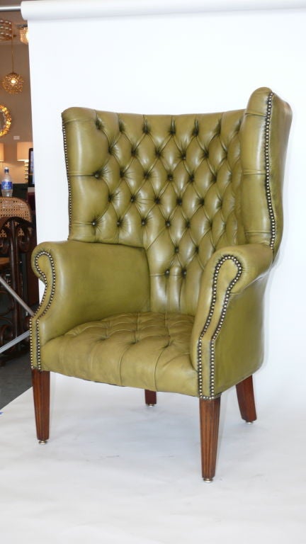 Incredible green leather wingback chair with curved back, wood legs and brass studs.  Unique original green leather with patina.