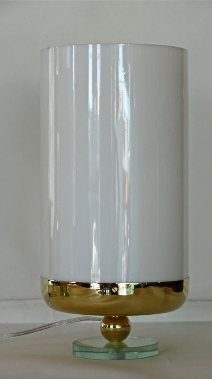 Unique pair of modern Italian hurricane table lamps. Large white cylinder opaque lucite shade sits in newly polished brass fixture and small green glass circular base. Newly re-wired.