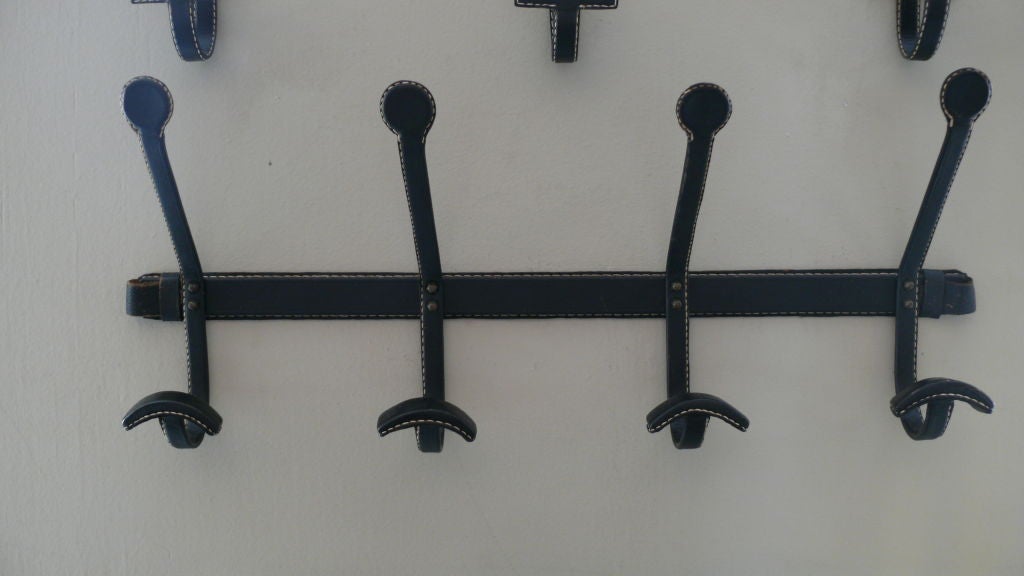 Beautiful Jacques Adnet black leather coat rack with 4 hooks fully covered in leather and white contrast stitching. Nice patina to leather.