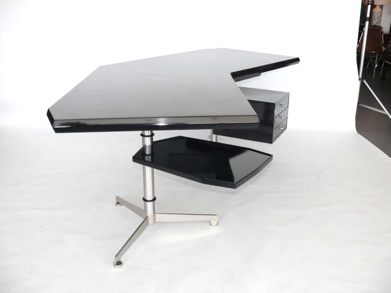 Fantastic black lacquered boomerang desk by Osvaldo Borsani. Pull out tray table revolves 360 degrees. The desk sits upon two tripod brushed nickel bases. Three drawer return on right side of desk as well as two pencil drawers that disappear into