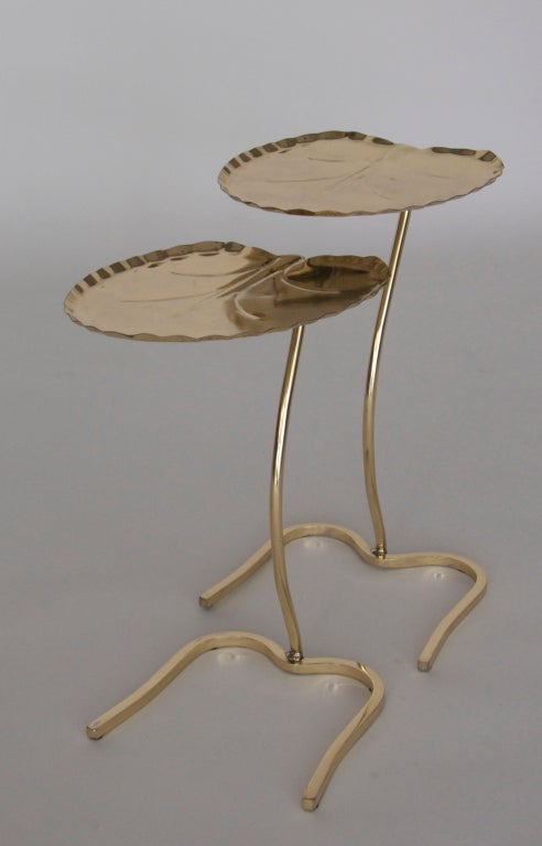 Fantastic pair of nesting tables by Salterini. Lily pad formed tables rest on slim curved stem and base. Newly polished brass finish. Beautiful set for any room. Large and small table priced as a pair. 2nd similar pair also available.