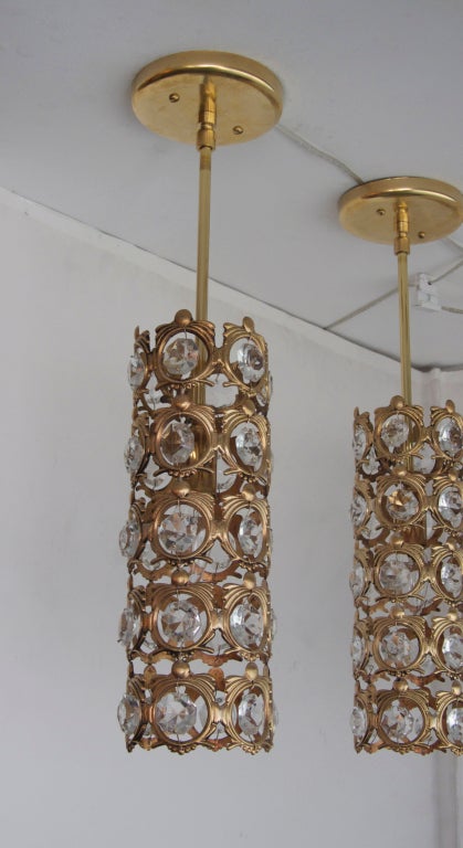Beautiful set of three Italian pendants. Slender tubular shape made of ornate brass  circles with hanging faceted crystals. Larger matching chandelier also available. Priced individually.