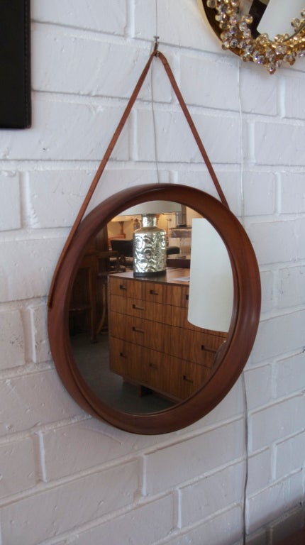 Gorgeous vintage Danish mirror hand carved from one solid piece of wood.  Natural finish to the wood and original leather strap.  Beautiful craftsmanship and sleek shape.