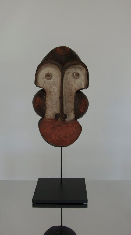 Great carved wood African tribal mask.  Beautiful coloration and texture to the mask, which sits on a sleek modern stand.