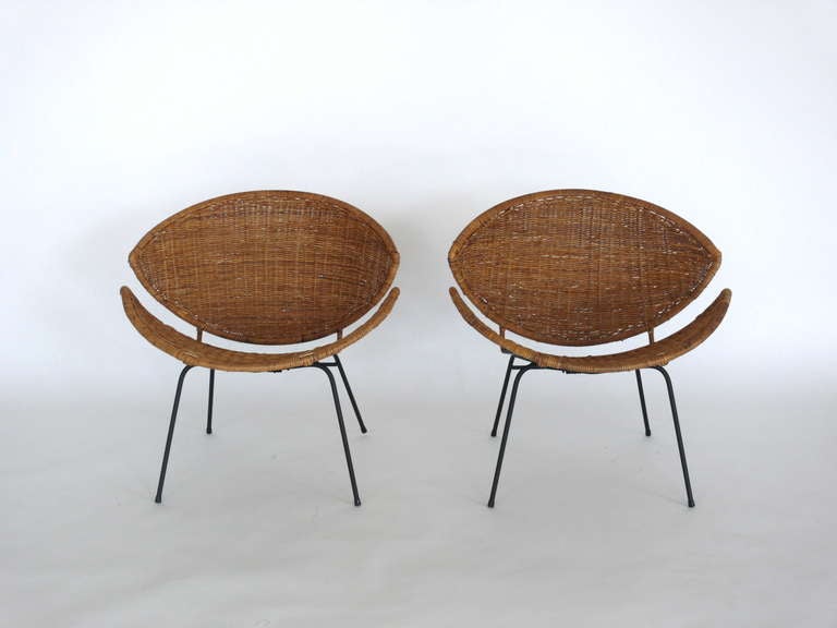 Sensational pair of wicker and iron scoop chairs designed by John Salterini. Woven wicker seat is in a scoop shape with slight open center. Newly painted black iron base. Beautiful combination of design and shape. Priced as a pair.
