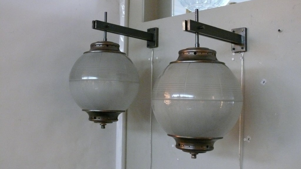 Suspended Azucena globe sconces with ribbed and textured glass and antique hardware.  Large in scale and beautiful patina to brass.  Even more breathtaking when illuminated!