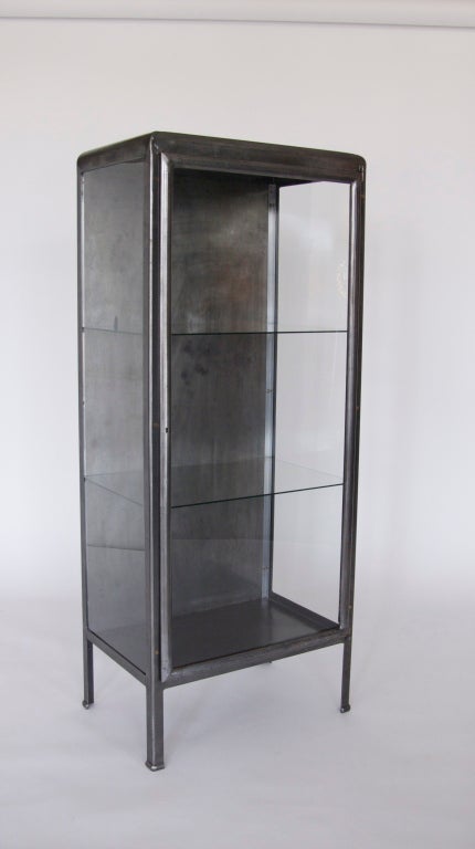 Wonderful iron and glass vitrine from France. Beautiful rounded corners and straight legs. Two deep glass shelves and a metal bottom surface. Great patina and industrial feel to the piece. Perfect display case, industrial bar, or storage for the