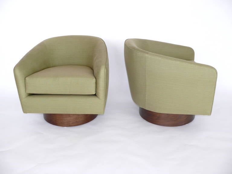 Beautiful pair of Milo Baughman swivel chairs. Original walnut wood bases have been newly refinished. Chairs have been newly reupholstered. Extremely comfortable and functional with a classic design.