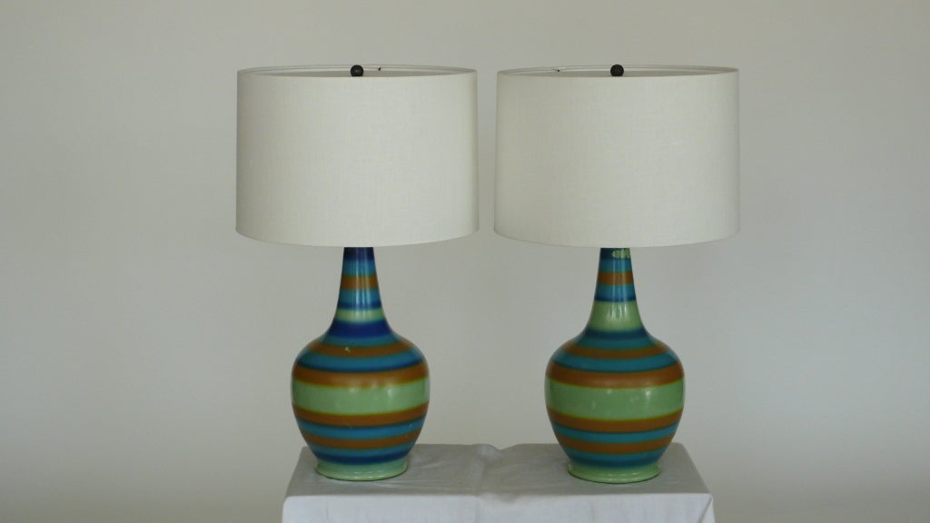 Great painted ceramic lamp with bulbous base and skinny neck. Striking colors of blue, green and orange painted in horizontal stripes across surface. Newly re-wired with new linen shade. Some small chipping to paint. Only a single lamp available.