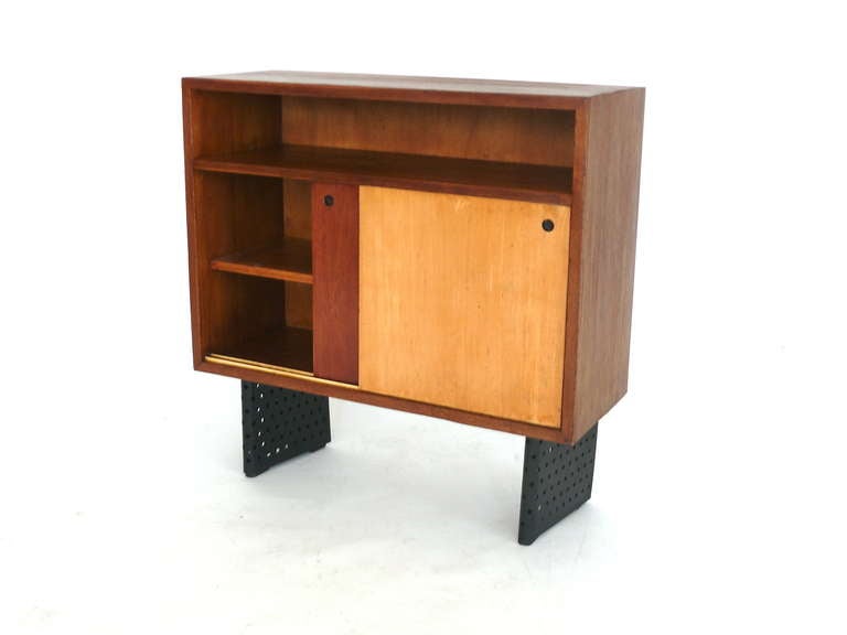 Gorgeous cabinet/bookcase designed by Escande, a student of Prouve. The cabinet is made of oak and rests on perforated black painted steel legs. Designed for the Anthony building in Strasbourg, France. Original wood finish with original muted red