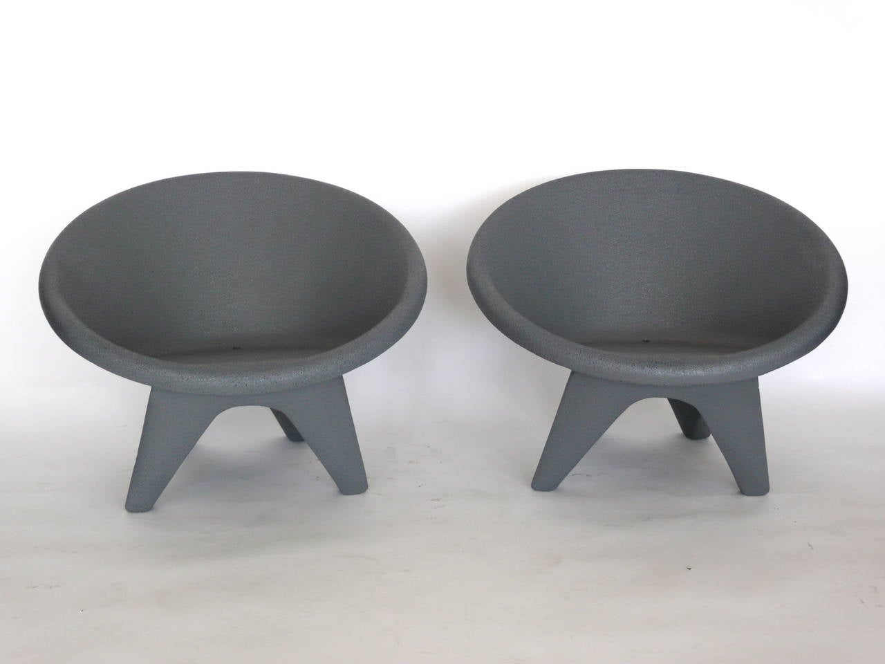 Unique pair of French concrete chairs. Angular base with four legs. Rounded frame with low profile seating. Newly painted in grey. Great lines. Perfect for the outdoor seating area or pool.