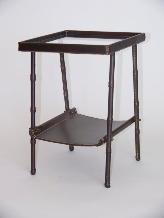 Beautiful side table by Jacques Adnet. All original dark brown leather with signature white contrast stitching. Fully covered leather bamboo legs support glass table with leather frame and lower leather shelf - perfect for magazines or books. Great