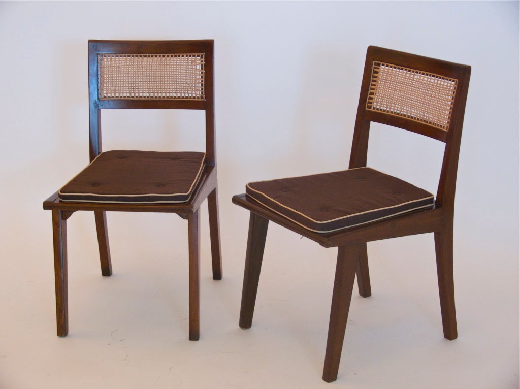 Incredible dining chairs by French designer Pierre Jeanneret. Refinished solid teak frame with woven caned seat and back. Upholstered brown cotton seat cushion with piping. Incredible angular legs and lines. From the Himalayan Student Residences in