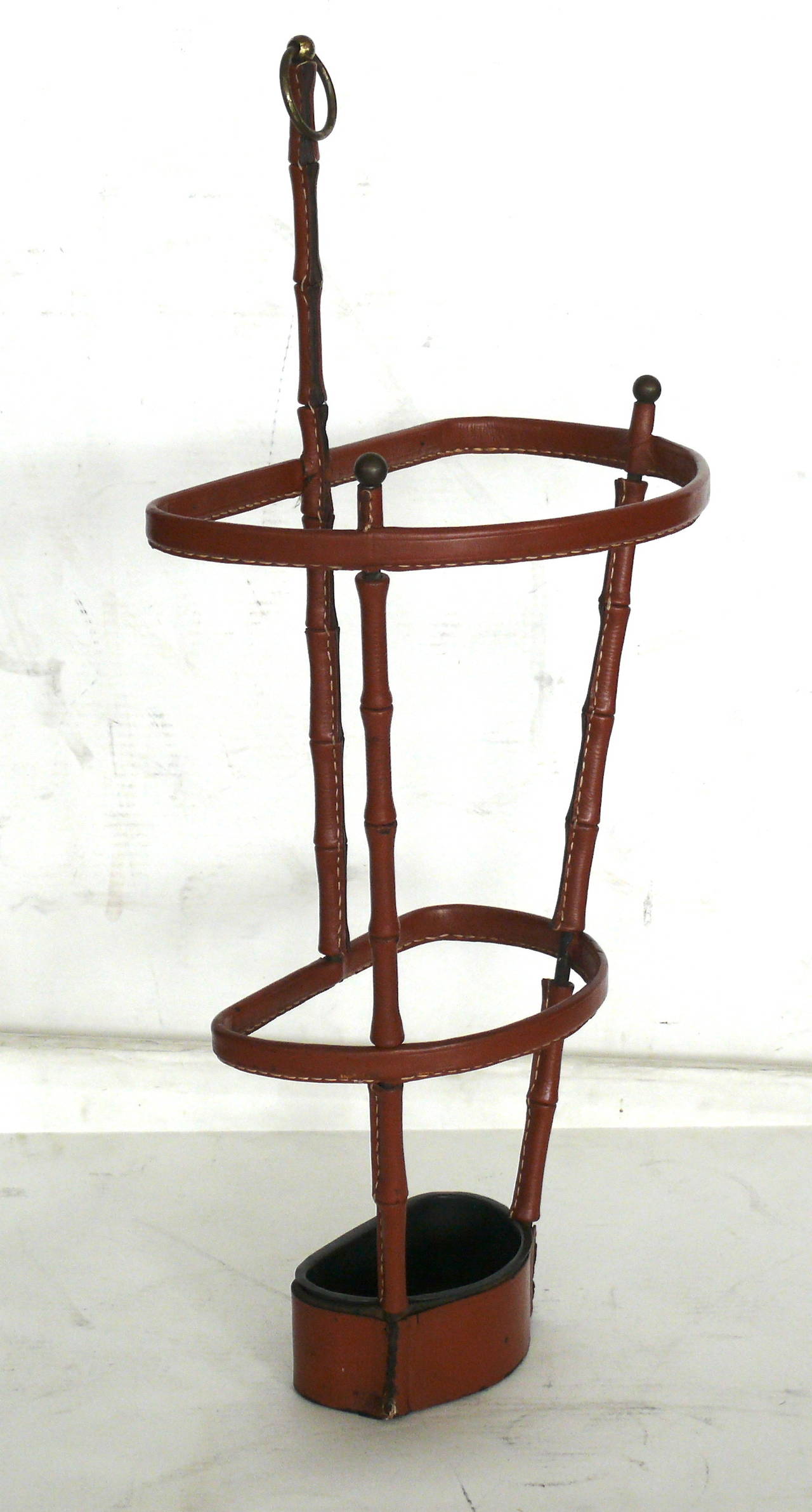 Handsome leather umbrella stand by Jacques Adnet. Saddle leather has signature Adnet contrast stitching and beautiful patina. Inset iron dish at the base to collect water. Excellent vintage condition. Very rare piece.