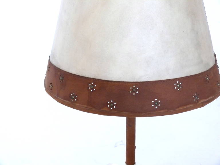 Unique brass and suede lamp with three legged base. Lamp features an original parchment and suede shade with perforated pattern in suede. Newly re-wired. Good vintage condition.