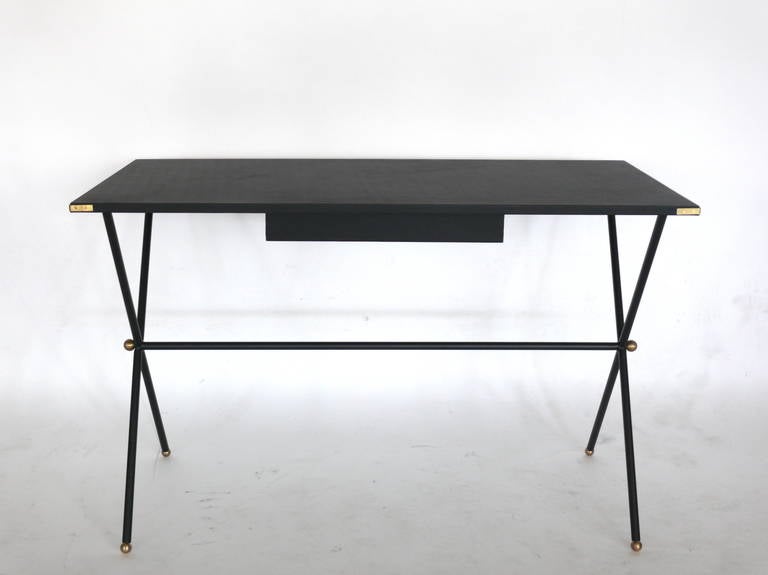 Beautiful black writing desk in the style of Jacques Adnet. Rectangular black lambskin top with brass corners sits on iron 