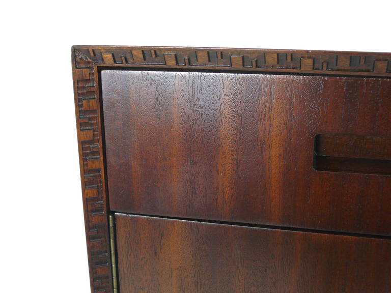 Handsome highboy dresser by Frank Lloyd Wright manufactured by Heritage Henredon. 5 pullout drawers. Top drawer contains jewelry tray. Large swing open doors have ample storage within. Distinct carvings from the Taliesin Line which was named after