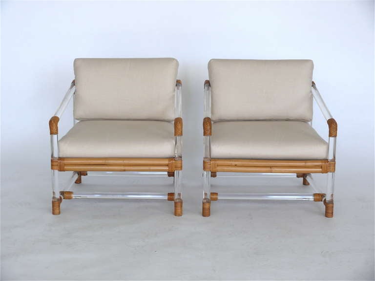 Stylish pair of lucite and bamboo club chairs by McGuire for Four Seasons. Lucite tubular frame is wrapped with bamboo throughout. Newly upholstered cream linen cushions compliment the simple design and fantastic mix of materials.