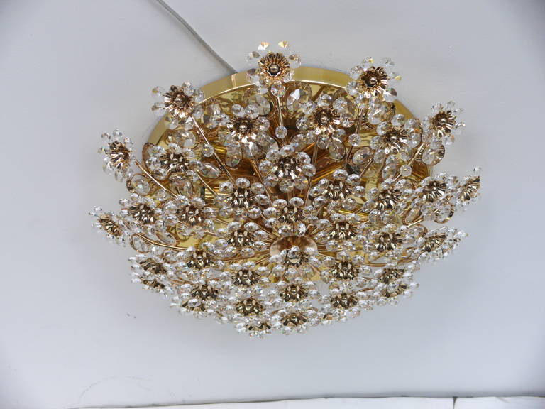 Elegant brass and crystal flush mount by Palwa. Numerous crystal and brass flowers extending from brass frame. Excellent vintage condition. Newly re-wired. Smaller matching flush mount also available.