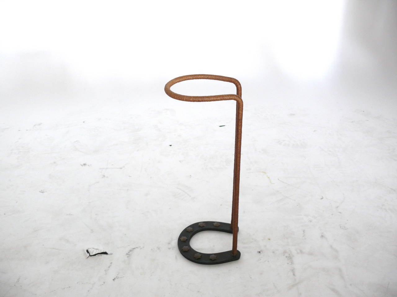 Handsome umbrella stand by Jacques Adnet. Horseshoe base with 7 metal stars affixed. Hemp wrapped frame completes the stand. Excellent vintage condition. Very unique piece.