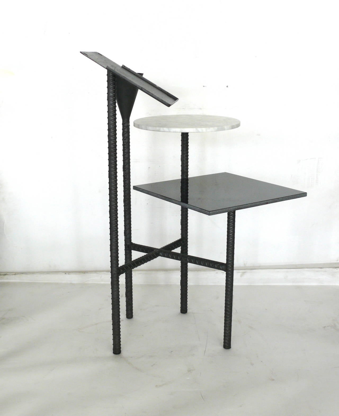 Very unique pair of telephone stands by Phillipe Starck. Rebar base with square black granite side table. Round Carrara marble table and metal candleholder. Metal tray perfect for a book or magazine. Excellent vintage condition.
