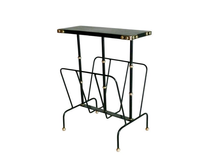 Handsome Jacques Adnet side table and magazine rack. New black leather top with brass corners rests on three iron and brass bamboo supports. Lower iron magazine rack on four leg iron base with brass ball feet. Stunning accent piece.