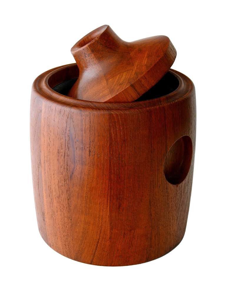 A beautifully made, staved teak ice bucket, designed by Henning Koppel for Georg Jensen. Koppel abandoned his usual Biomorphism here for a more functional approach. The piece is dominated by the three circles cut into the teak; the one on top allows