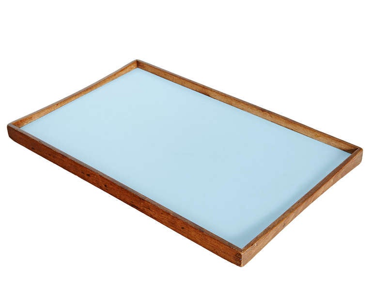 Finn Juhl designed these useful trays for Torben Ørskov in 1957. Their frames are Siamese teak, carefully joined, while their working surfaces are in melamine -- one face is black, the other (reversibly) a very light blue. The profile of the teak