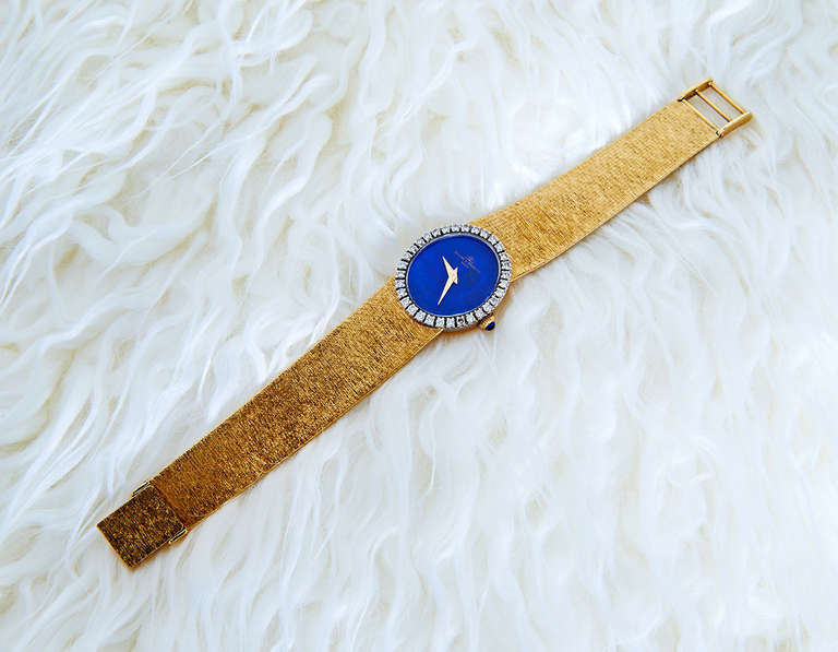 This glamorous 1970s Baume & Mercier lady's watch has an oval Lapis Lazuli face framed by 32 white round brilliant-cut diamonds, a sapphire-topped winding crown, and solid gold band. The movement is a 17-jewel Baume & Mercier mechanical calibre, and
