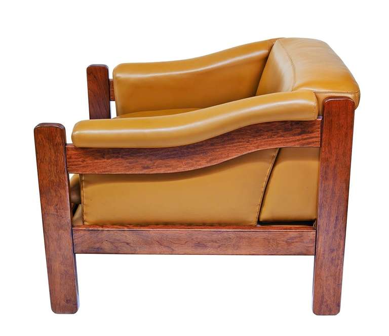 A pair of ingeniously constructed armchairs, with French-stitched leather upholstery and a gorgeously figured, golden mahogany frame. Luxurious.