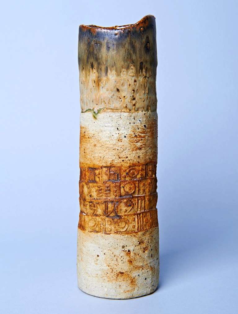 This cylindrical vase was coil built, its lower third unglazed and decorated with bands of impressed decoration resembling runic characters. This is a representative example of British studio ceramist Alan Wallwork's work from the late 1960s. Signed