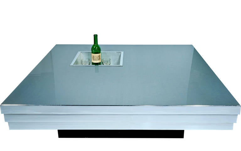 A futuristic coffee table by Pierre Cardin, with a brushed aluminum top, stepped chrome sides (a detail probably in hommage to Art Deco, which was the reigning obsession at the time), and an ebonized wood base. The recessed compartment can be used