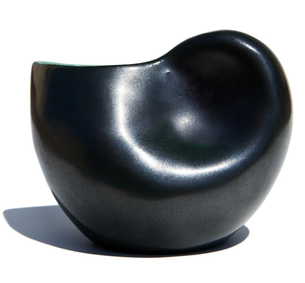 Probably intended as a small pitcher or a creamer, this charming vessel by Georges Jouve would serve well as an intimate vase on one's writing desk. Jouve's trademark matte black (slightly iridescent) enamel is tonally balanced by the interior