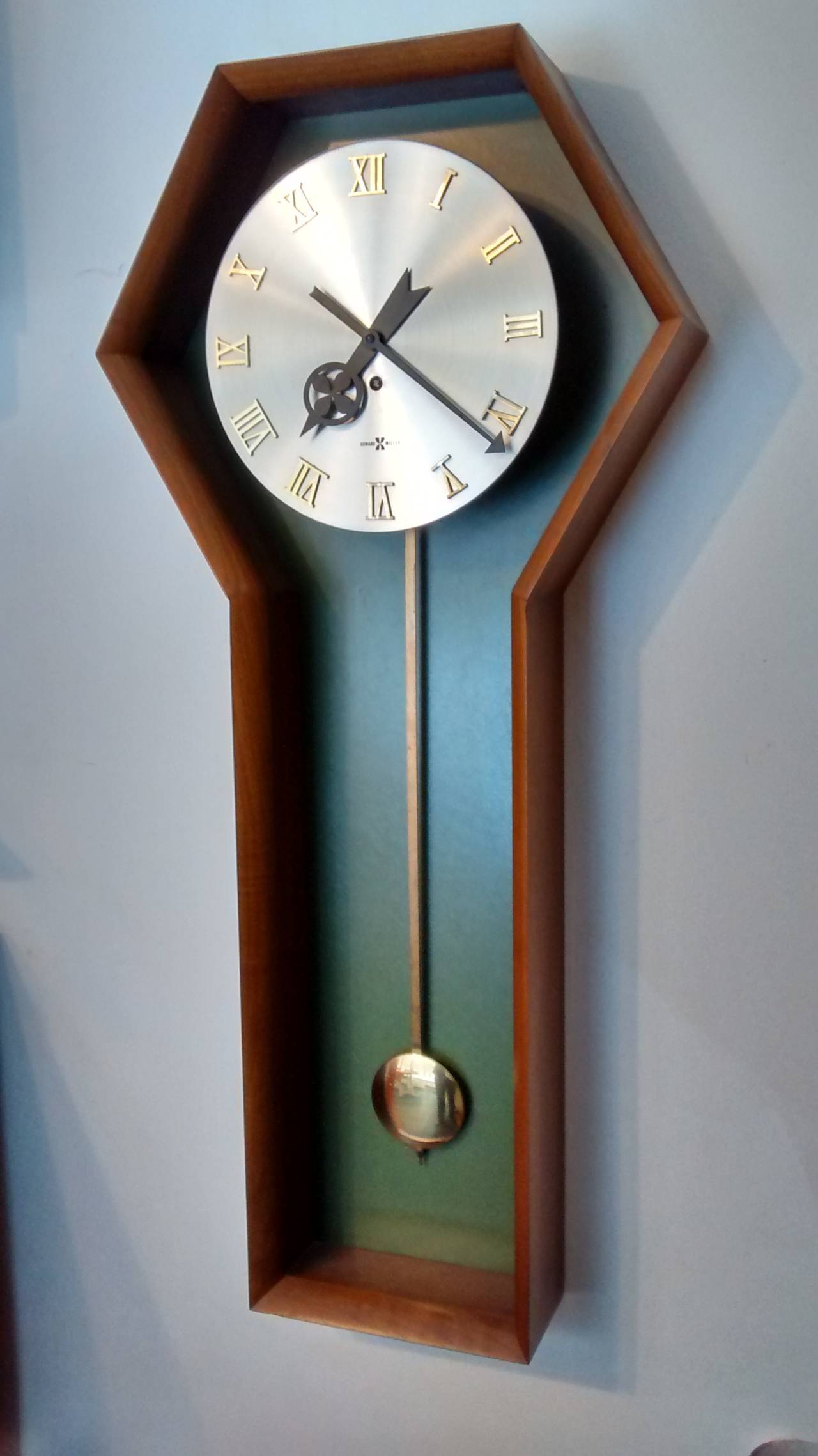 Superb recent find is this George Nelson designed wall mounted pendulum clock for the Howard Miller Clock Company of Zeeland, Michigan. 

Case rendered in American walnut, and shaped like a keyhole or coffin, this well known model is increasingly