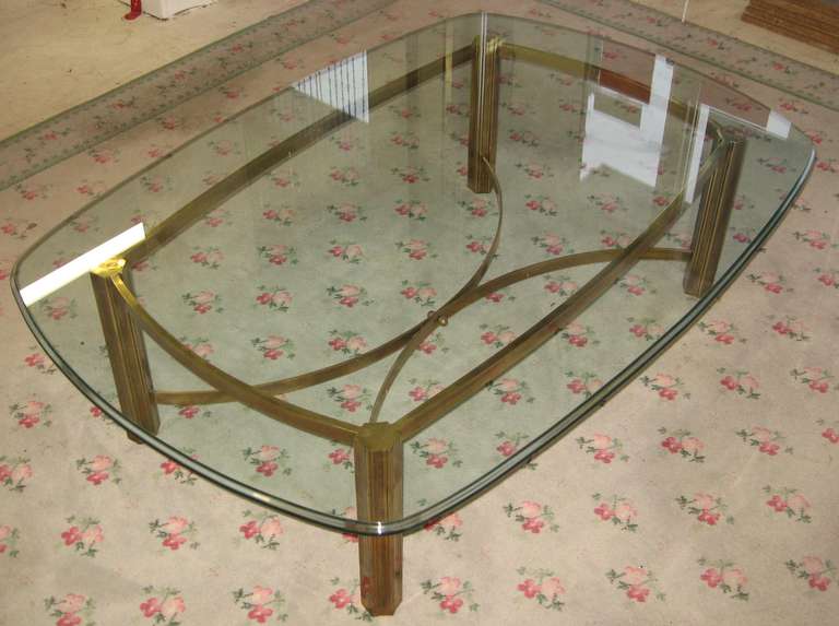 Wonderful solid antiqued brass Mastercraft coffee table, for Baker Furniture, dating to the early 1970's.  

Heavy duty brazed brass in an antique darker finish with the original bullnose glass top.

C-shaped stretchers meet in the middle and