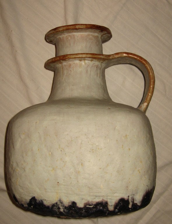 Giant handled vessel with a wonderful salt glaze attributed to Bruno Gambone, and dating to the early 60's.  Heavy duty pottery form with a pleasing drip glaze in a vaguely pale green/grayish color with caramel colored edging on handle and rim.