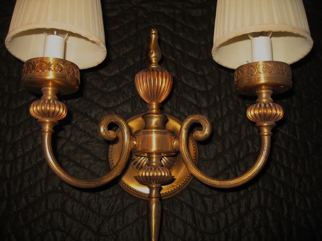 Late 1940's pair of French made high polished bronze two-light wall sconces, recently removed from their original location.  Heavy duty polished and lacquered bronze with original wiring, which was working when removed. Sockets were replaced in the